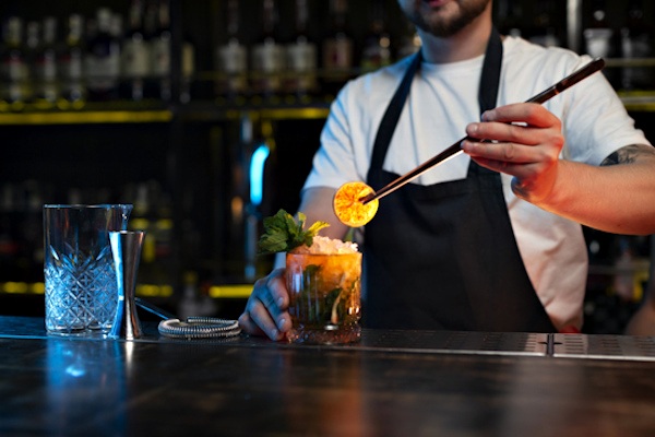 Barkeeper dekoriert gemixten Cocktail mit getrockneter Zitrone